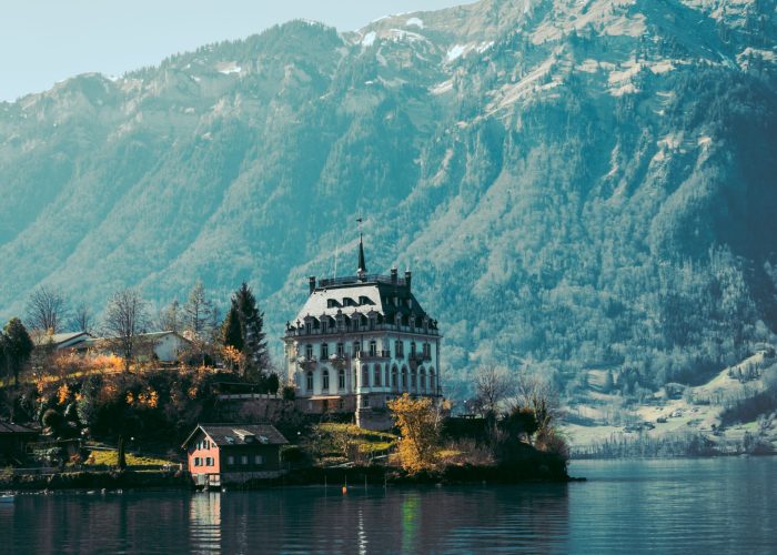 The Iseltwald castle on the Lake Brienz island with mountains on the background